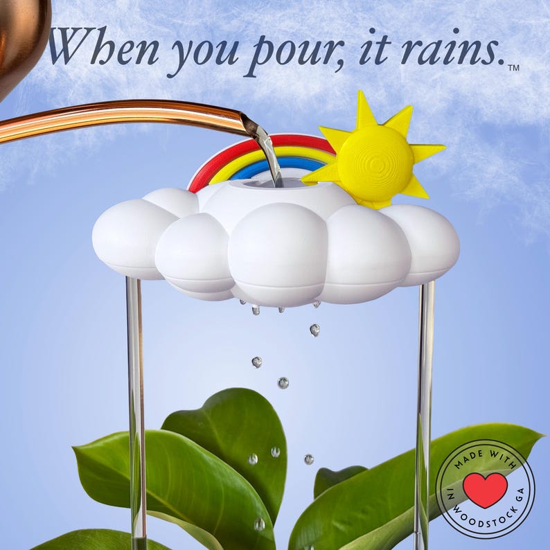 K&ouml;nnte beinhalten: Ein wei&szlig;es, wolkenf&ouml;rmiges Pflanzenbew&auml;sserungsger&auml;t mit einer gelben Sonne und einem Regenbogen. Wasser flie&szlig;t aus einem kupferfarbenen Auslauf in die Wolke und erzeugt einen Regeneffekt. Der Text "When you pour, it rains." ist oben zu sehen.