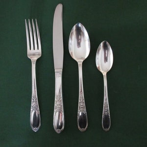 May include: A set of four silver-plated flatware pieces, including a fork, knife, and two spoons. The pieces have an ornate design with floral motifs.