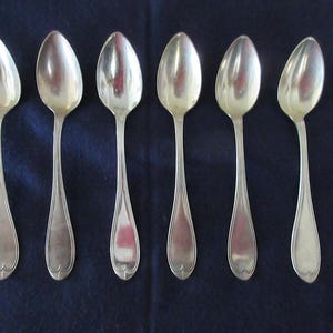 May include: Six silver teaspoons with heart-shaped bowls. The spoons are arranged in a row, with the handles pointing to the right.