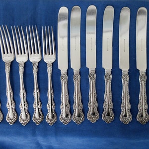 May include: A set of ten silver-plated flatware pieces, including eight forks and two butter knives. The forks have ornate handles with a floral design. The knives have a similar design on the handles and are slightly longer than the forks.
