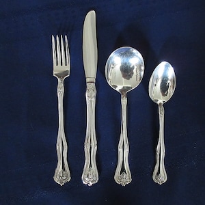 May include: A set of four silver-plated flatware pieces, including a knife, fork, and two spoons, on a blue background.