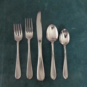 May include: A five-piece stainless steel flatware set consisting of a salad fork, a dinner fork, a dinner knife, a soup spoon, and a teaspoon. Each piece features a polished, reflective silver finish with a smooth, tapered handle design.