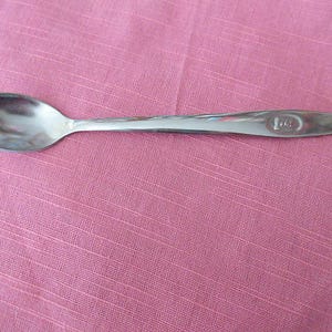 Peut inclure: Une cuillère à café en argent avec un bol arrondi et un long manche. Le manche porte la gravure "L.G.".