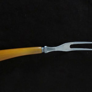 May include: A yellow plastic handled stainless steel carving fork.