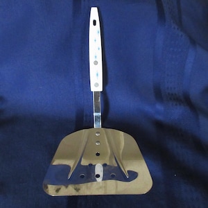 May include: A silver spatula with a white handle and blue accents. The spatula has a slotted design and is ideal for flipping pancakes or other delicate foods.