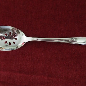 May include: A silver serving spoon with a slotted bowl and a floral design on the handle.
