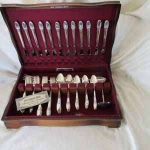 Juego de cubiertos de plata de 78 piezas, serie 12, para almuerzo, de Rogers, 1847, modelo FIRST LOVE, con banda decorativa en la punta del pecho y flor. En buen estado, con ligero uso.