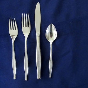 May include: A set of four silver-plated flatware pieces, including a knife, fork, and spoon, on a blue background.