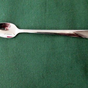 May include: A silver spoon with a rounded bowl and a long, slender handle.