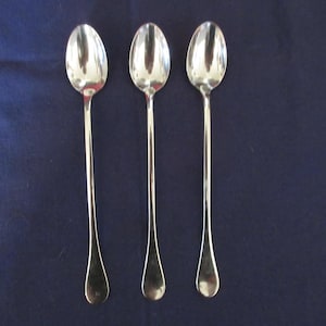 May include: Three silver spoons with rounded bowls and long, slender handles.