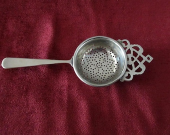Colador de té elegante de mano de 17 cm (6 3/4"), plateado sin marca, con mango marcado "England". Buen estado.