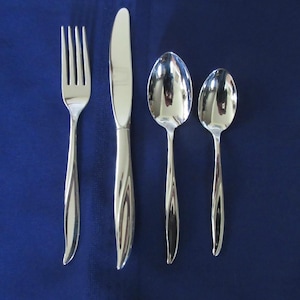 Könnte beinhalten: Ein Set aus vier Edelstahl-Besteckteilen: eine Gabel, ein Messer und zwei Löffel. Das Besteck hat eine glänzende, reflektierende Oberfläche und ein gedrehtes Griffdesign. Der Hintergrund ist einfarbig dunkelblau.