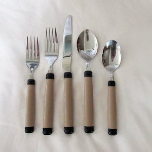 May include: Set of five silver-toned cutlery pieces with brown plastic handles. The set includes a knife, two forks, and two spoons.
