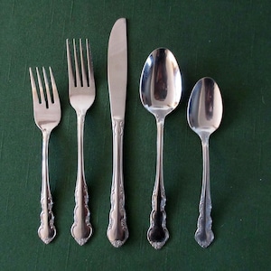 May include: A set of five silver-plated utensils, including a knife, two forks, and two spoons. The utensils have ornate handles with a floral design.