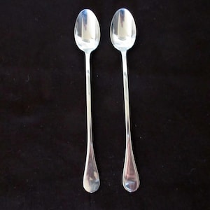 May include: Two silver spoons with rounded ends and long handles.