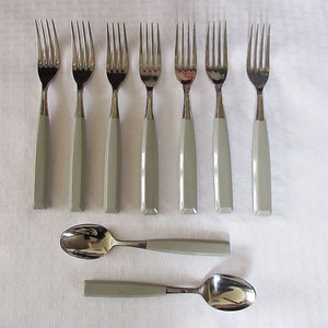 May include: Set of ten silver forks and two spoons with gray handles. The forks and spoons are arranged in two rows on a white tablecloth.