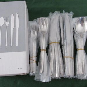 Può includere: Un set di posate in acciaio inossidabile in una scatola, con singoli pezzi avvolti nella plastica. La scatola mostra illustrazioni di cucchiai, forchette e coltelli. Il set include cucchiai, forchette e coltelli.