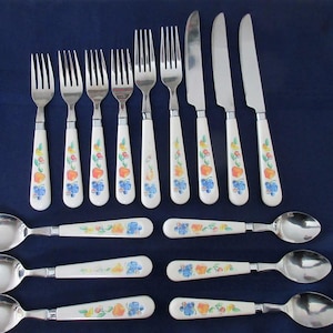 May include: A complete set of vintage silverware with white handles decorated with colorful fruit and floral patterns. The set includes forks, knives, and spoons, perfect for a formal dining experience.