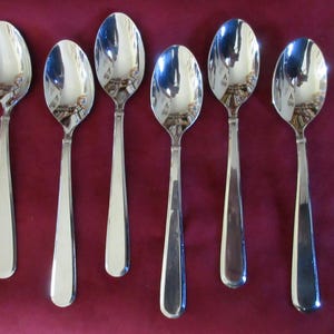 May include: Six silver teaspoons with a polished finish. The spoons have a rounded bowl and a long, slender handle.