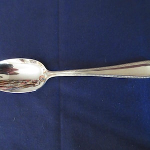 May include: A silver spoon with a beaded edge and a rounded bowl.