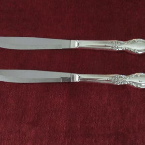 Wm Rogers/International Silverware のシルバープレート ステーキナイフ 2 個、ビクトリア朝のローズ柄、ローズ センターハンドル、スクロール付き、「現状有姿」