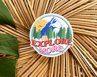 May include: A colorful sticker with a mountain scene, a tent, and the text "EXPLORE MORE" in a retro font.