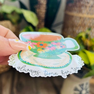 May include: A green teacup and saucer with a floral pattern and the text "always time for tea".