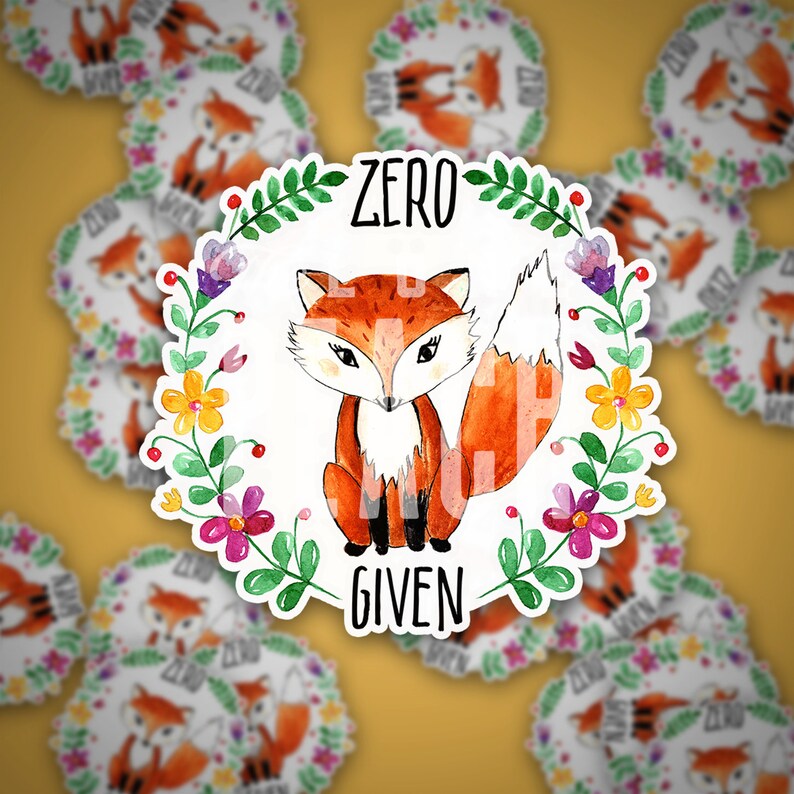 Pode incluir: Um adesivo branco com uma ilustra&ccedil;&atilde;o em aquarela de uma raposa com uma coroa de flores ao redor. O texto "Zero F***s Given" est&aacute; escrito no adesivo.