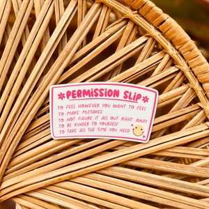 Puede incluir: Pegatina rosa y blanca con el texto "*Permission Slip*" y una lista de declaraciones de permiso: "To feel however you want to feel", "To make mistakes", "To not figure it all out right away", "To be kinder to yourself", "To take all the time you need". Un icono de cara sonriente est&aacute; al lado de la &uacute;ltima declaraci&oacute;n.