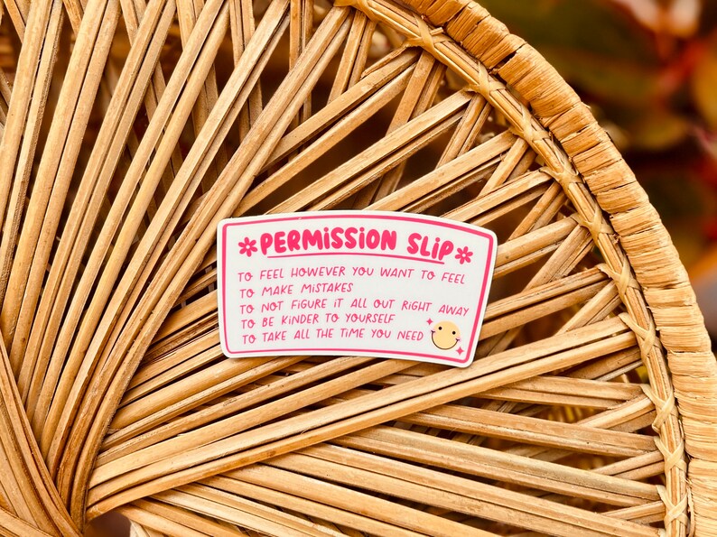 Puede incluir: Pegatina rosa y blanca con el texto "*Permission Slip*" y una lista de declaraciones de permiso: "To feel however you want to feel", "To make mistakes", "To not figure it all out right away", "To be kinder to yourself", "To take all the time you need". Un icono de cara sonriente est&aacute; al lado de la &uacute;ltima declaraci&oacute;n.