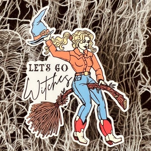 K&ouml;nnte beinhalten: Eine Cartoon-Illustration einer Frau mit Cowboyhut und Stiefeln, die auf einem Besen reitet mit dem Text "Let's Go Witches".