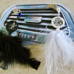 May include: Two car air freshener dreamcatchers with feathers. One is black with a blue bead and the other is white. Both have a silver clip to attach to the air vent.