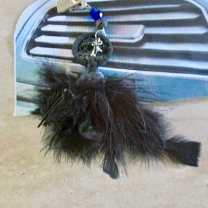 May include: Black feather car charm with a blue and silver beaded accent and a black metal charm with a palm tree design.