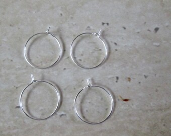 May include: Four silver hoop earrings, each with a simple circular design.