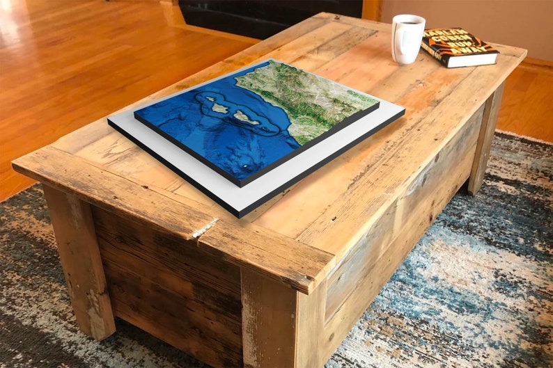May include: A wooden coffee table with a distressed finish. A framed map of a coastal region is on top of the table.