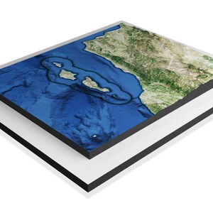 May include: A 3D relief map of a coastal area with a large island in the center. The map is blue and green, with a black frame.