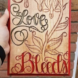 10x12 engraved bleeding heart flower with script lettering written &quot;love bleeds&quot; stained and sealed.