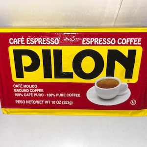 May include: A rectangular brick of Pilon espresso ground coffee in a red and yellow package. The label features the text CAFÉ ESPRESSO, ESPRESSO COFFEE, PILON, CAFÉ MOLIDO, GROUND COFFEE, 100% CAFÉ PURO, 100% PURE COFFEE, and NET WT 10 OZ (283g).