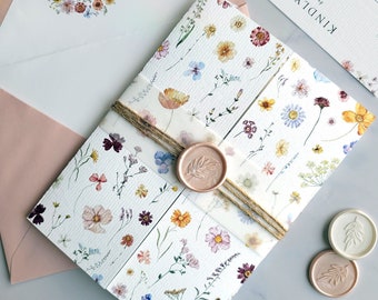 May include: A folded wedding invitation with a floral pattern and a wax seal. The invitation is tied with twine and has the text "KINDLY REPLY by 09 July 2028".