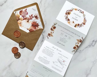 May include: A folded wedding invitation with a fall theme. The front of the invitation features a wreath of leaves, pumpkins, and flowers. The text on the front reads "Olivia & Jamie". The inside of the invitation includes details about the wedding, including the date, time, and location. The back of the invitation includes a map and a RSVP card.