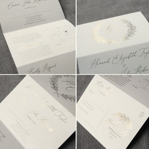 May include: A white wedding invitation suite featuring gold foil lettering and botanical wreath accents. The set includes a folded card with event details, a map, and a response postcard with lines for guest names and dietary requirements.