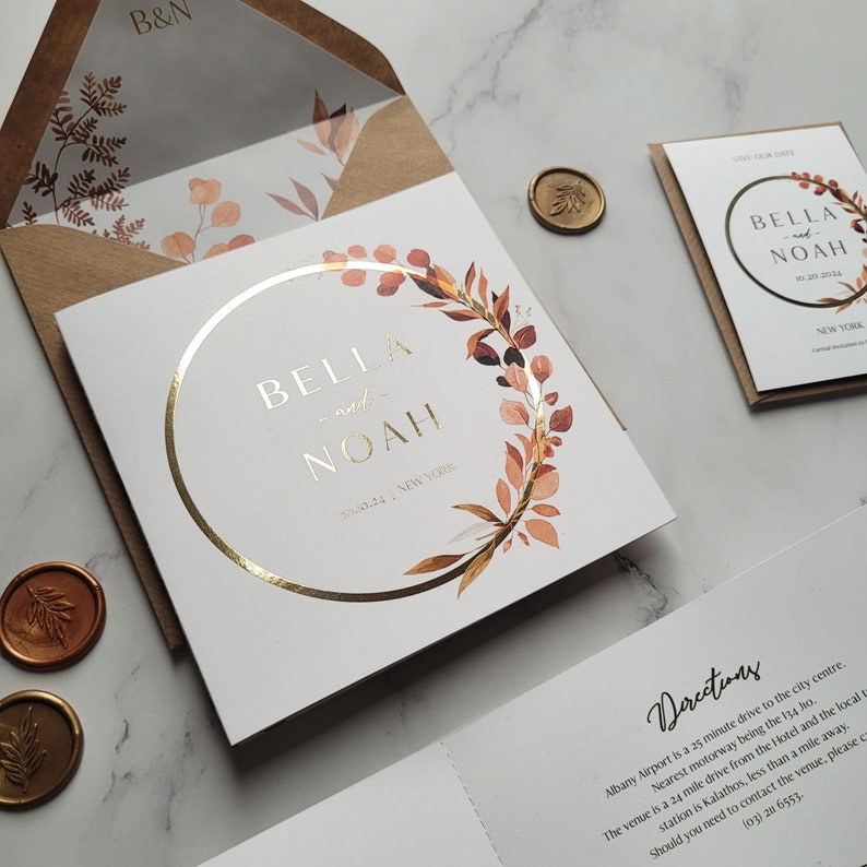 May include: A white wedding invitation with a gold circle and a watercolor floral wreath. The names "Bella and Noah" are written in gold script inside the circle. The date "3.10.24" and the location "New York" are written below the names. The invitation also includes directions to the venue.