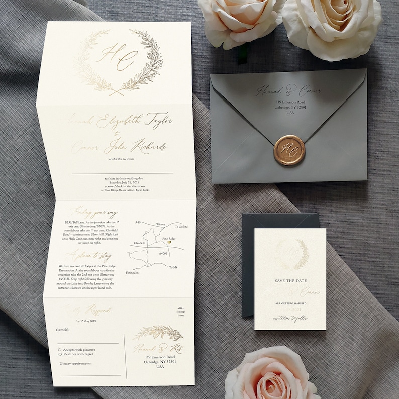 May include: A cream-colored tri-fold wedding invitation with gold foil lettering and a wreath motif, a gray envelope with a gold wax seal, and a matching save-the-date card. The invitation includes a map, event details, and an RSVP section.