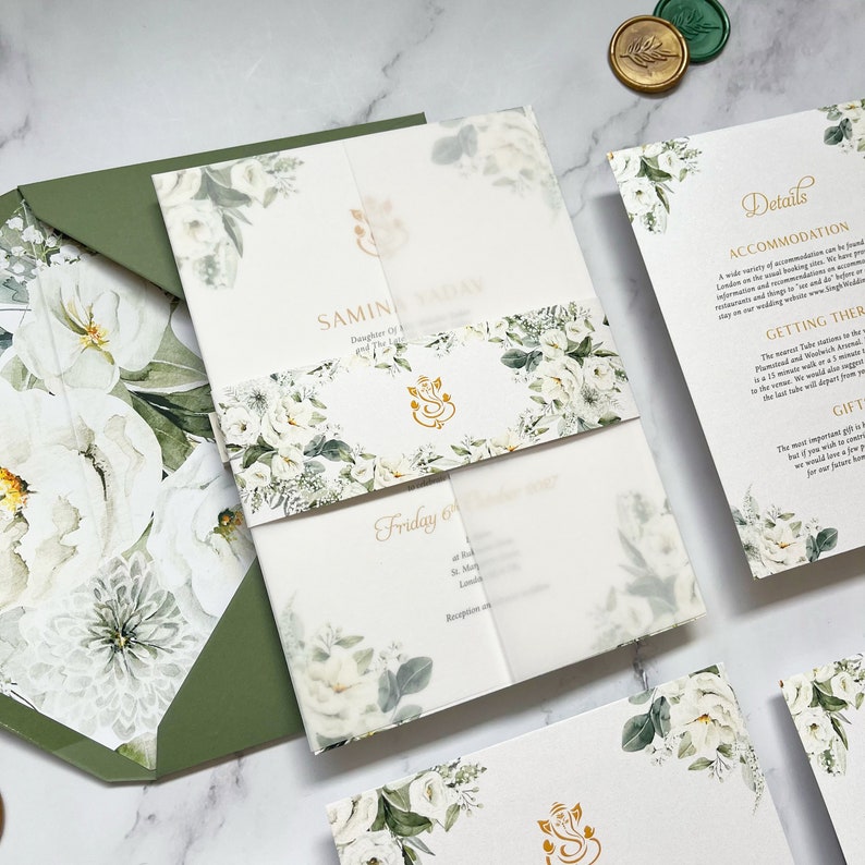 May include: A white wedding invitation with green foliage and white flowers. The invitation includes the names "SAMIN" and "ADAV" and the date "Friday 6".