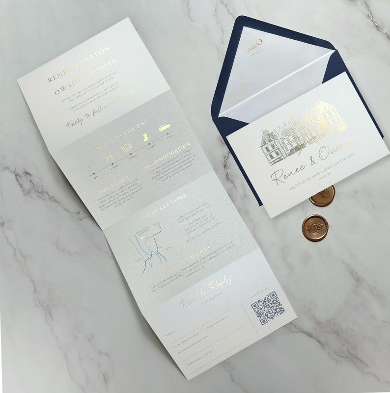 May include: A wedding invitation suite featuring a tri-fold card with gold foil text and a map, alongside a rectangular card with a gold foil illustration of a chateau, a navy blue envelope with gold monogram, and two round bronze wax seals.