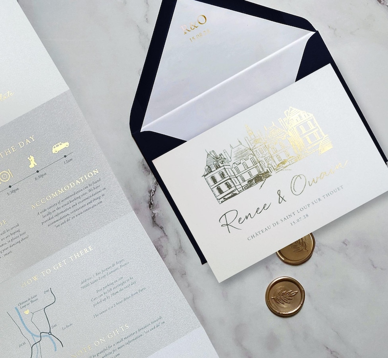 May include: A white wedding invitation card with gold foil architectural illustration and the text Renee & Owain, Chateau de Saint Loup sur Thouet, 15.07.28. Includes a dark blue envelope with gold R&O text and two gold wax seals with leaf imprints.