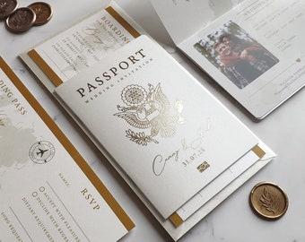 May include: A wedding invitation set designed as a passport, featuring a gold foil eagle emblem on a white cover with the text Passport Wedding Invitation, Cammy & Jack, and 31.07.28. Includes a boarding pass RSVP card and wax seals.