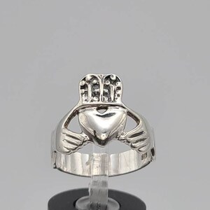 May include: A silver Celtic Claddagh ring with a heart, two hands, and a crown. The ring is on a white background.