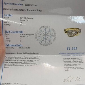 May include: An appraisal document for a diamond ring. The document includes details such as the carat weight, cut, color, and clarity of the center and side diamonds. The ring is 14K yellow gold. The estimated retail replacement value is $1,295.