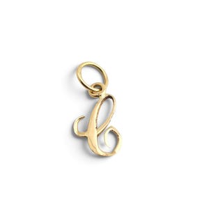 May include: A gold-coloured metal charm in the shape of the cursive letter C. The charm features a polished, reflective surface and includes a small, circular jump ring attached to the top, allowing it to be easily suspended from a chain or bracelet.